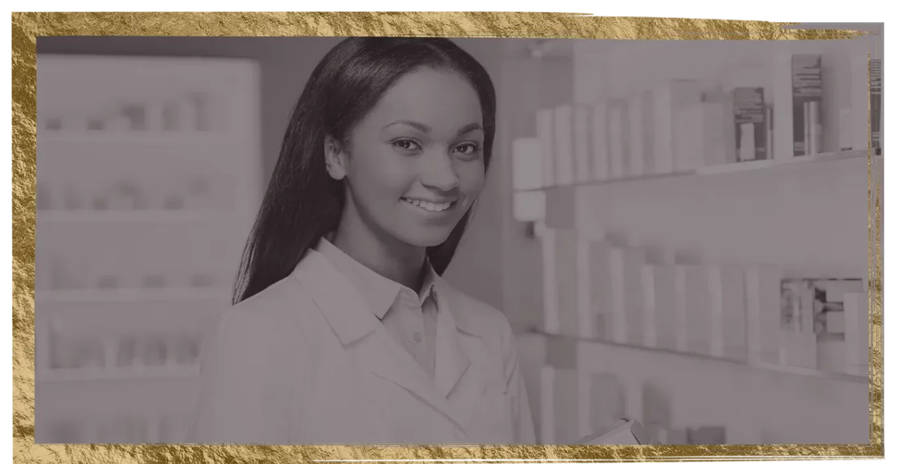 A woman in a lab coat is smiling in front of a shelf of cosmetics.